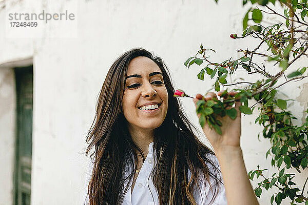 Schöne Frau lächelt  während sie einen Pflanzenzweig hält