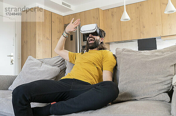 Fröhlicher Mann mit Virtual-Reality-Headset zu Hause