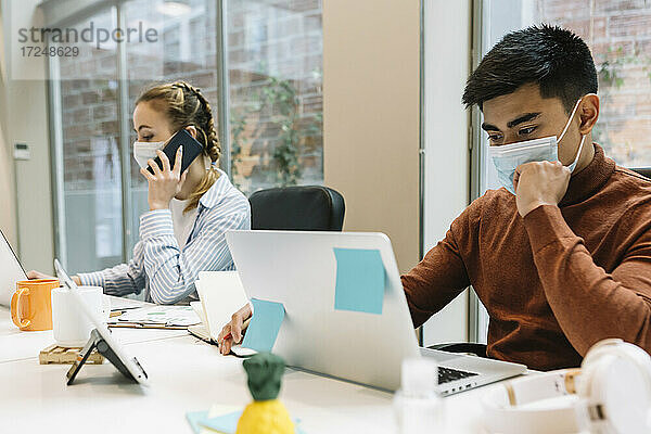 Männliche und weibliche Fachkräfte tragen bei der Arbeit im Büro einen Mundschutz