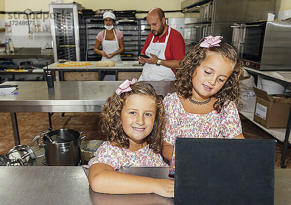 Zwillinge lächelnd  während sie mit ihren Eltern in einer Großküche stehen