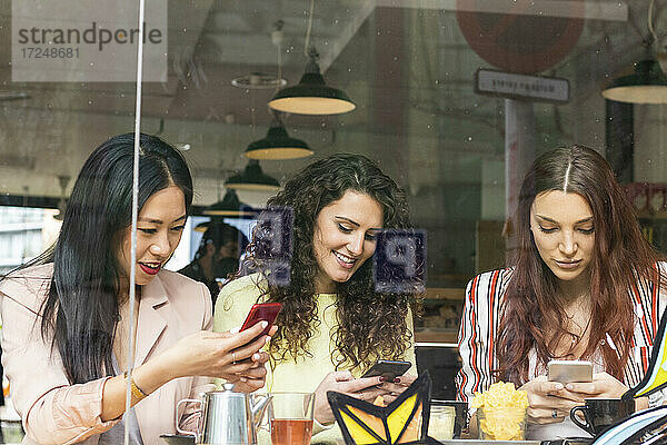 Junge Frauen benutzen Mobiltelefone in einem Café