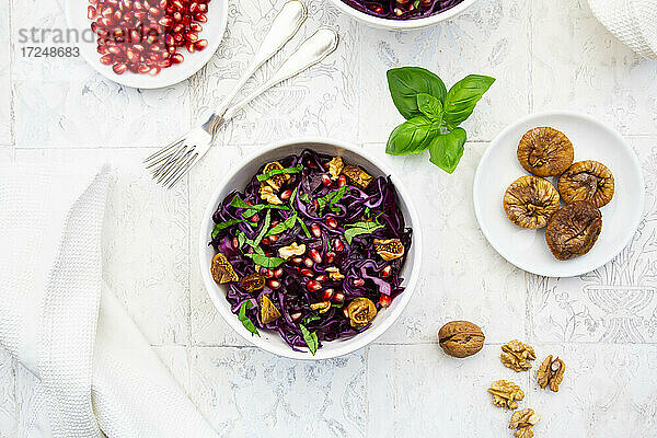 Schüssel mit veganem Salat mit Rotkohl  Granatapfelkernen  getrockneten Feigen  Walnüssen und Basilikum