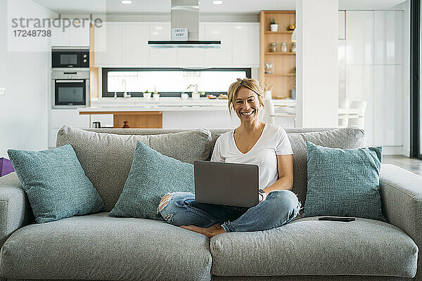 Geschäftsfrau mit Laptop  während sie zu Hause auf dem Sofa sitzt