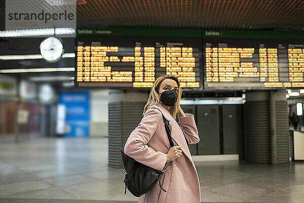 Mittlere erwachsene Frau mit Gesichtsschutzmaske auf einem Flughafen