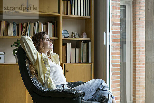 Entspannte Frau sitzt auf einem Stuhl zu Hause
