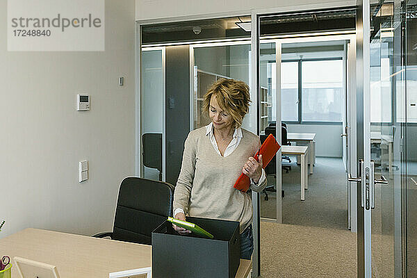 Unternehmerin schaut in den Terminkalender  während sie ihren Schreibtisch im Büro einrichtet