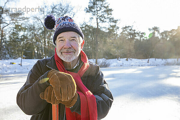 Älterer Mann mit Handschuhen hält Hockeyschläger im Freien