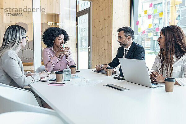 Multiethnische männliche und weibliche Fachleute diskutieren während einer Sitzung im Büro
