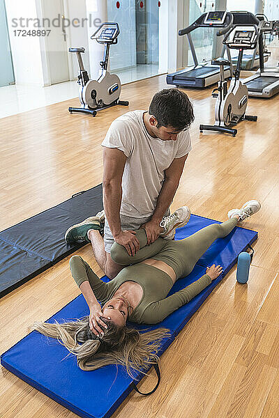 Sportler hilft seiner Freundin beim Training im Fitnessstudio