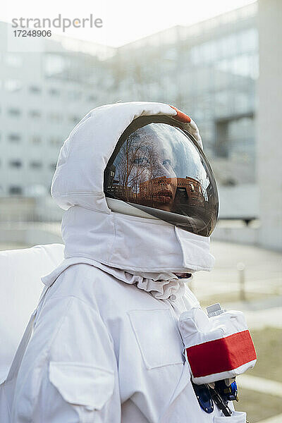 Weibliche Astronautin im Raumanzug schaut in der Stadt weg