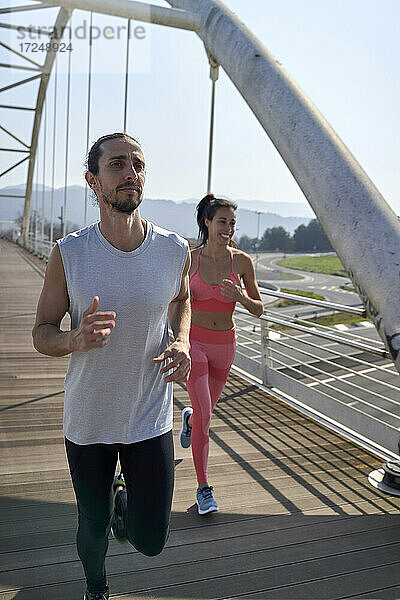Männlicher und weiblicher Sportler beim Joggen auf einer Brücke