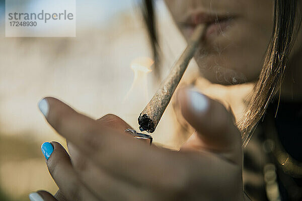 Junge Frau zündet Marihuana-Zigarette im Freien an