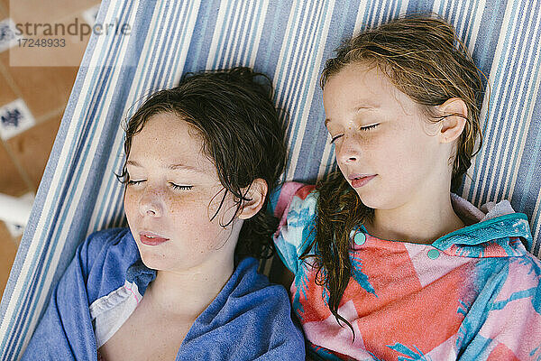 Bruder und Schwester im Bademantel schlafen in der Hängematte