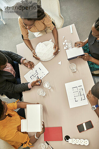 Männliche und weibliche Architekten diskutieren über ein Modell während einer Besprechung am Schreibtisch in einem Coworking-Büro