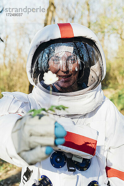 Lächelnde Astronautin mit Blume im Wald