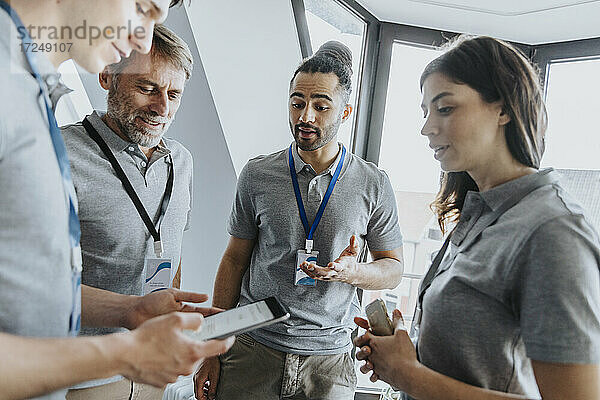 Männlicher Fachmann  der während einer Konferenz über ein digitales Tablet mit Kollegen diskutiert