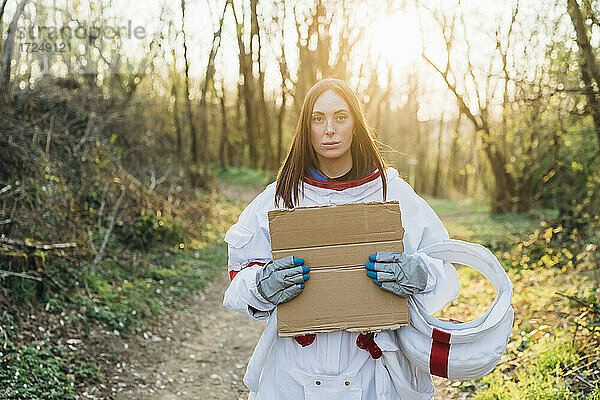 Junge Astronautin hält Karton im Wald