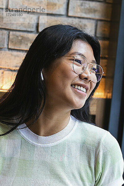 Lächelnde Frau mit Brille  die im Café wegschaut