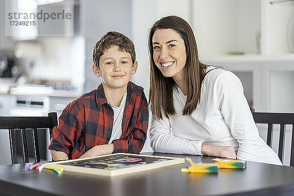 Lächelnder Junge sitzt mit seiner Mutter am Küchentisch