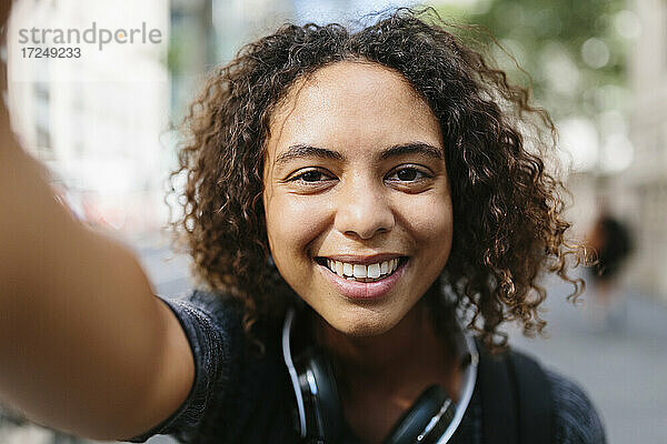 Frau mit lockigem Haar macht Selfie in der Stadt