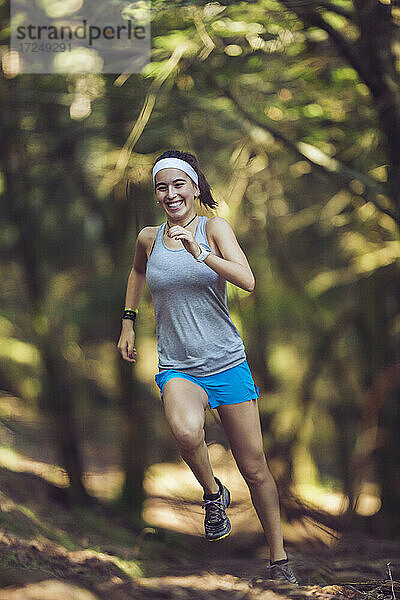 Lächelnde junge Sportlerin beim Laufen im Wald