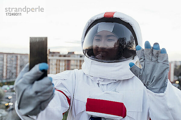 Junge Astronautin winkt bei einem Videogespräch über ein Smartphone