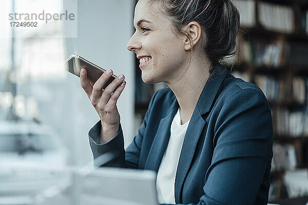 Lächelnde Geschäftsfrau  die in einem Café mit einem Mobiltelefon spricht