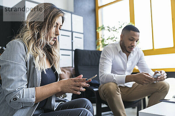 Männliche und weibliche Unternehmer nutzen Mobiltelefone im Coworking-Büro