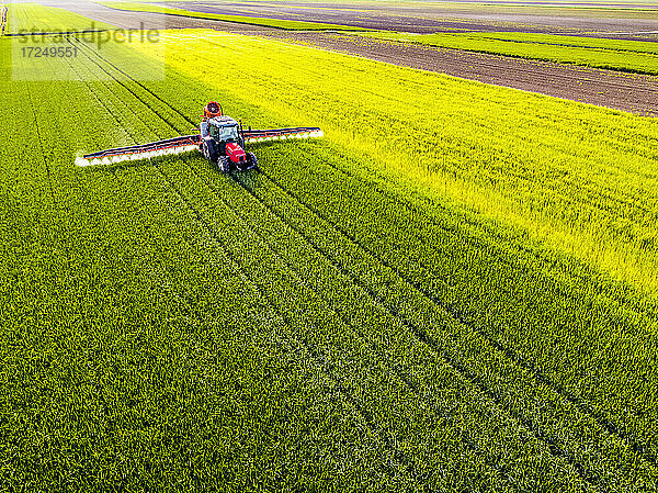 Pflanzenschutzspritze beim Besprühen von Weizen mit Pestiziden