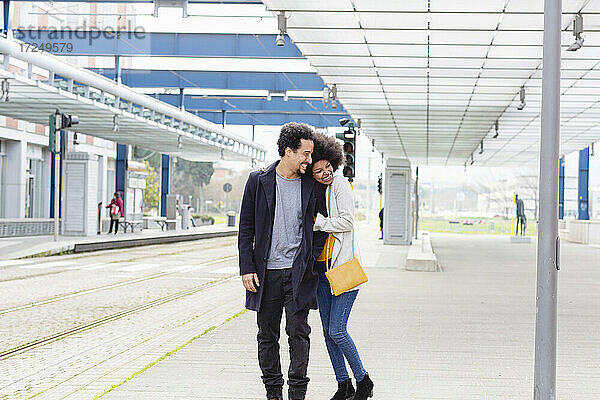 Fröhliches Paar  das sich am Bahnhof umarmt