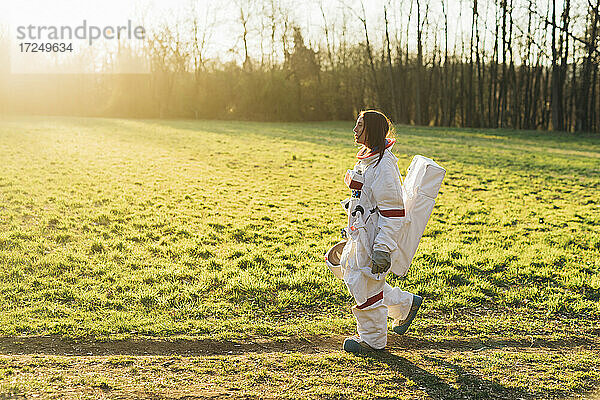 Weibliche Astronautin im Raumanzug  die an einem sonnigen Tag durch Grasland spaziert