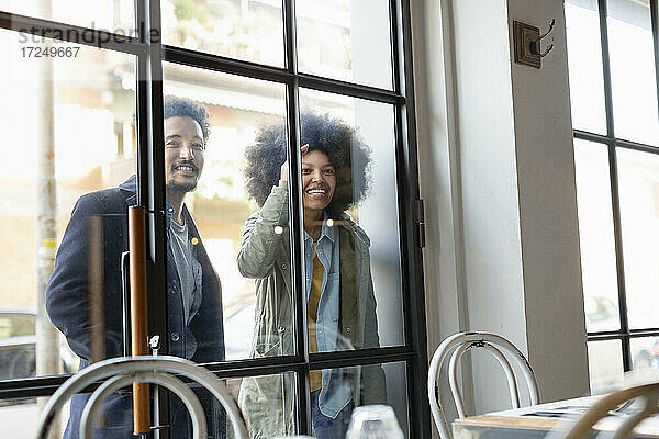 Paar schaut durch ein Glasfenster ins Innere eines Cafés