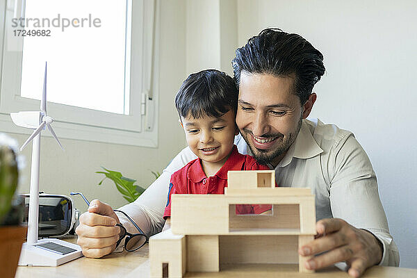 Männlicher Architekt und Sohn lächelnd bei der Betrachtung eines Hausmodells