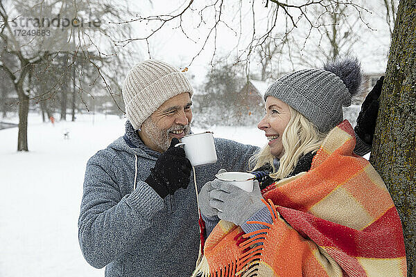 Lächelndes älteres Paar  das im Winter Tee in einer Tasse trinkt