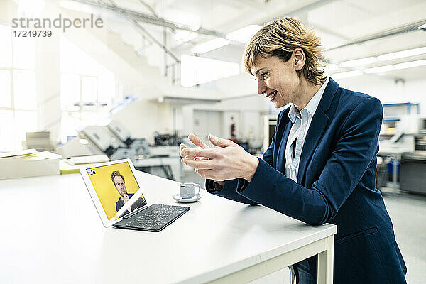 Lächelnde Geschäftsleute  die bei einem Workshop per Videoanruf über ein digitales Tablet diskutieren