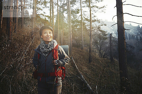 Mittlere erwachsene Frau lächelt beim Wandern im Wald