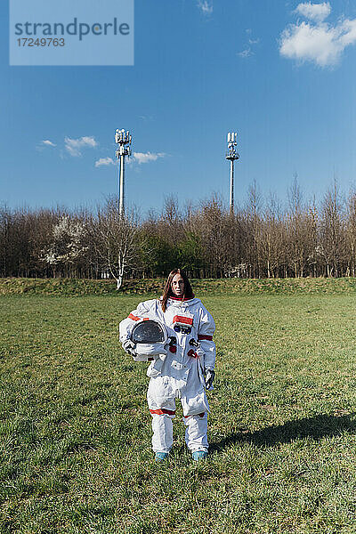Weibliche Astronautin hält Weltraumhelm auf Grasfläche