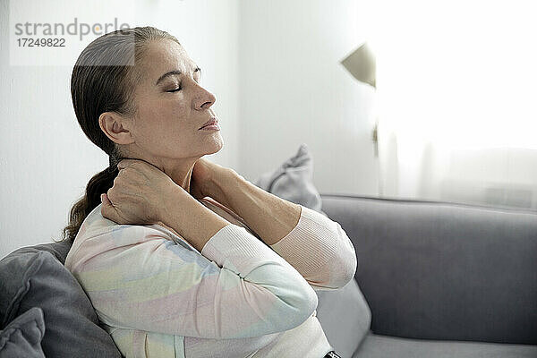 Müde Frau  die mit geschlossenen Augen auf dem Sofa sitzt