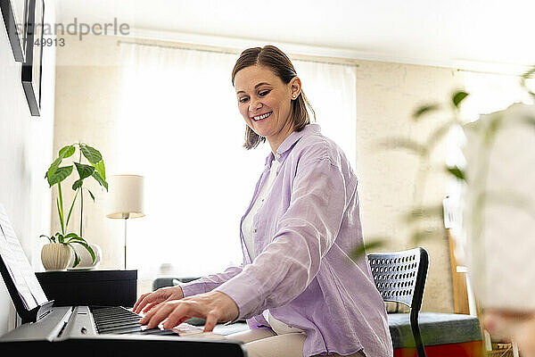 Lächelnde Frau lernt zu Hause Klavier