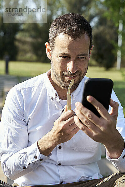 Geschäftsmann lächelt während eines Videoanrufs über ein Mobiltelefon im Park