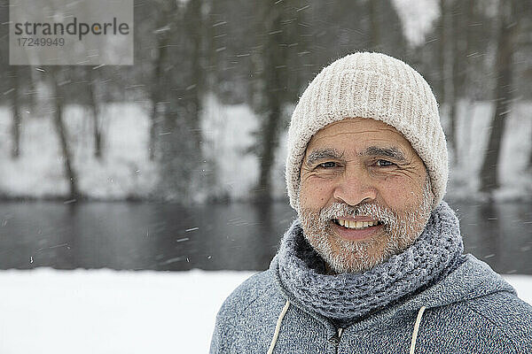 Älterer Mann mit Strickmütze  der im Winter lächelt
