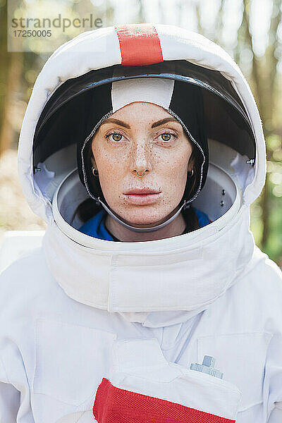 Weibliche Astronautin mit Weltraumhelm und -anzug im Wald