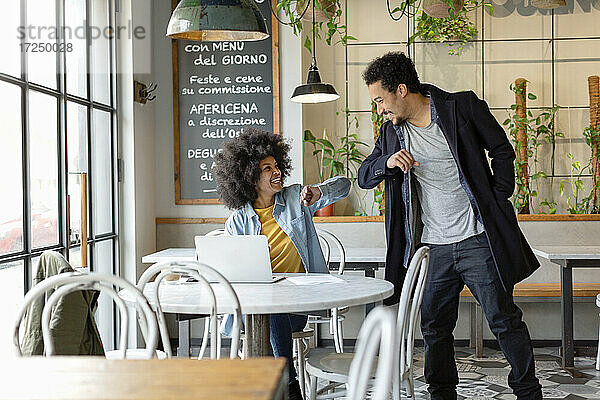 Geschäftsfrau stößt männlichen Mitarbeiter im Café mit dem Ellbogen an