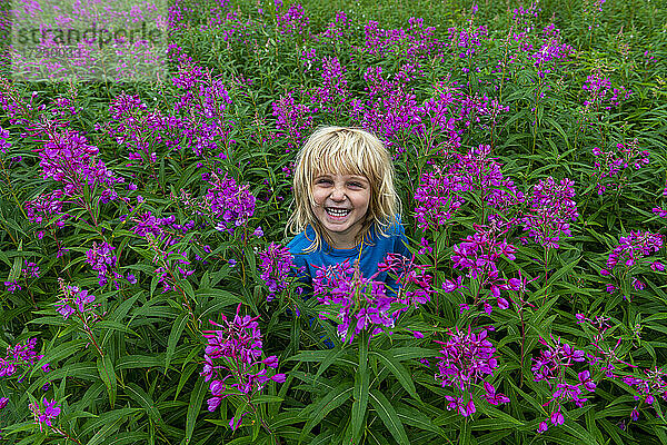Lächelndes Mädchen inmitten eines blühenden Blumenfeldes