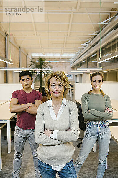 Männliche und weibliche Fachkräfte mit verschränkten Armen im Coworking-Büro