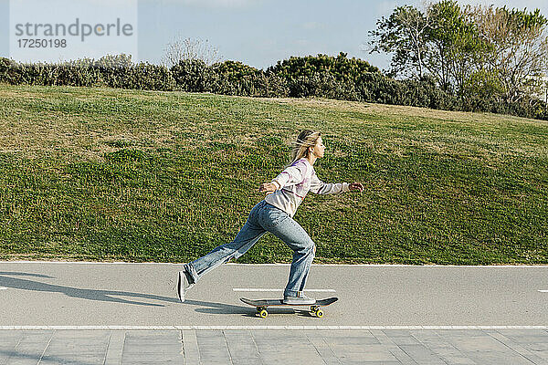 Mittlere erwachsene Frau  die auf der Straße Skateboard fährt