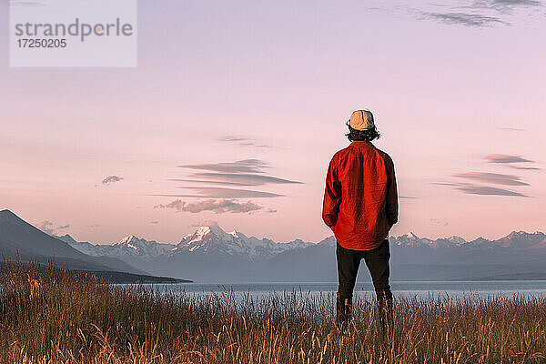 Neuseeland  Canterbury  Rückansicht eines jungen Mannes mit Blick auf den Lake Pukaki bei Sonnenuntergang