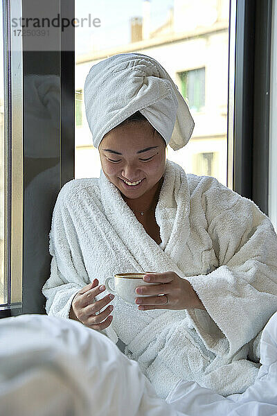 Lächelnde Frau mit Kaffeetasse im Hotel