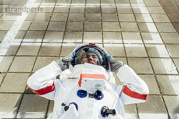 Junge Astronautin im Raumanzug auf dem Gehweg liegend