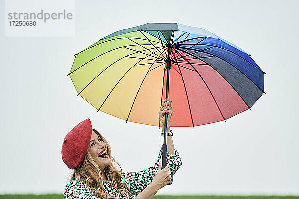 Lächelnde Frau hält mehrfarbigen Regenschirm